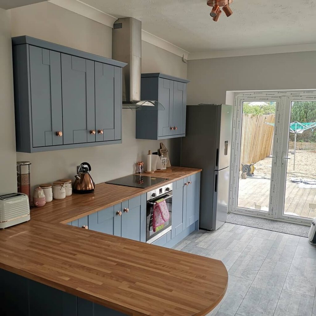 Blue cabinets and light wooden worktops that our kitchen fitting services installed